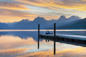 Couple on dock at Sunrise at Lake McDonald Glacier National Park Montana