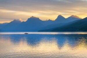 Canoeist paddling on Lake McDonald at sunrise. Glacier National Park Montana