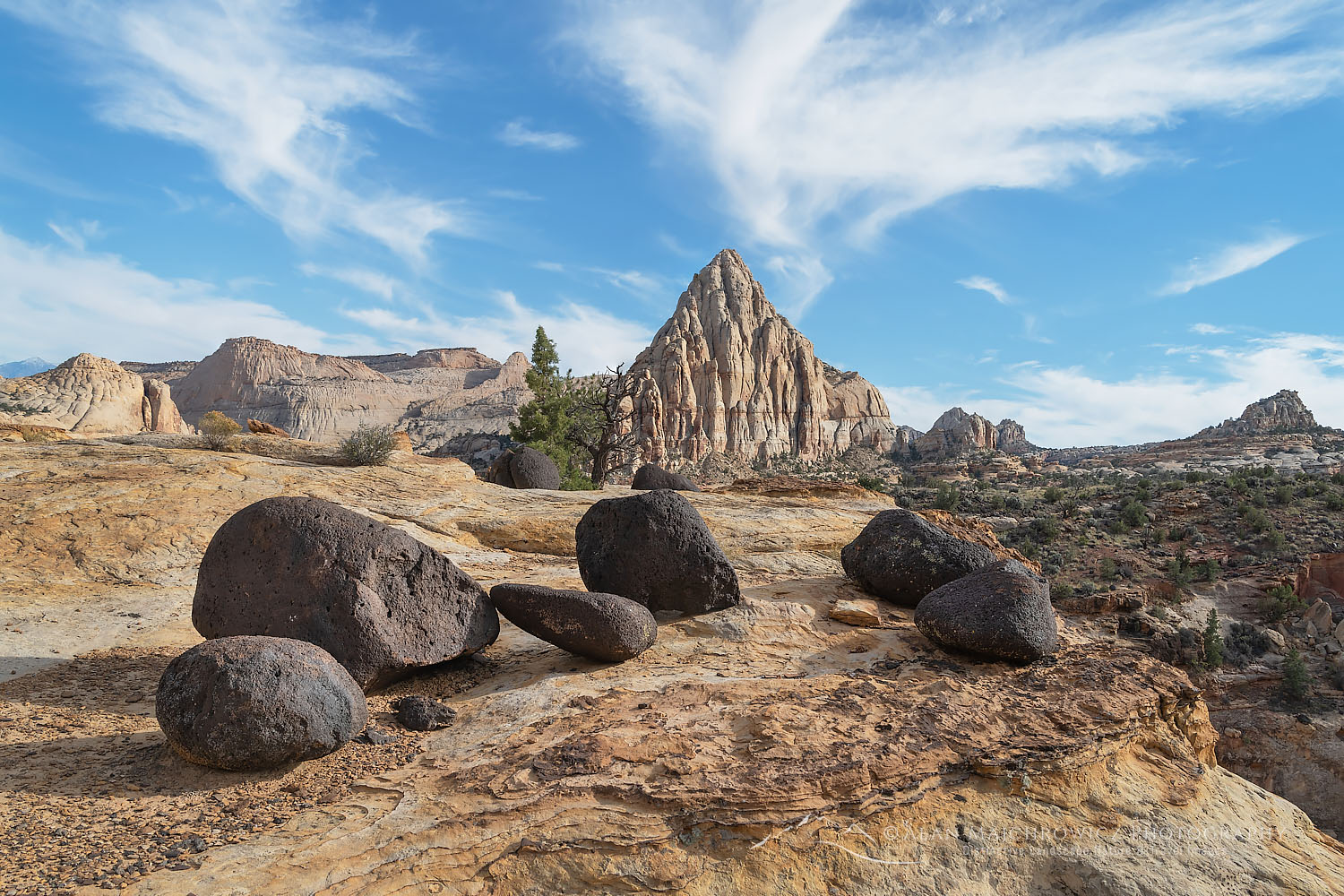 Pectols Pyramid and black lava boulders on striated sandstone slickrock. Capitol Reef National Park Utah #75356