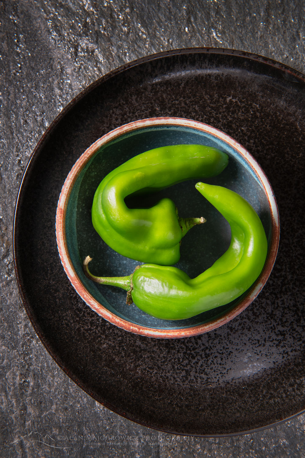 Arrangement of Hatch Chile peppers with stoneware bowl on stone backdrop #81232