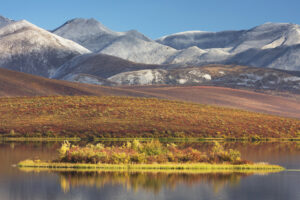 Lake in the Blackstone Plateau reflected clouds and hills of the Ogilvie Range, Yukon Canada