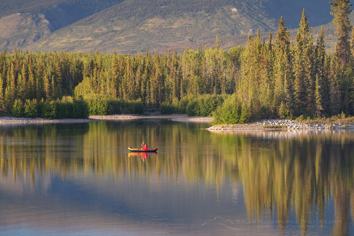 A man fly fishing in a red raft on Boya Lake. Tā Ch'ilā Park (Boya Lake Park), British Columbia #86931