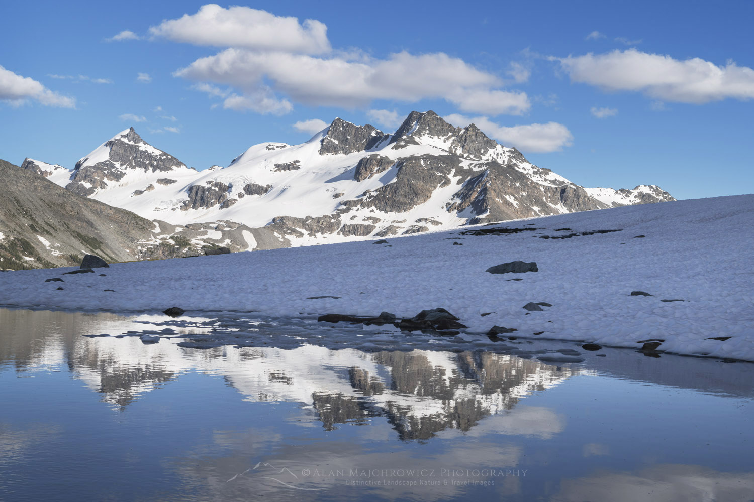 Snow melt tarn on Silent Mountain. Twin Towers, Cony Peak, and Spillimacheen Glacier are in the distance. Purcell Mountains British Columbia #86124