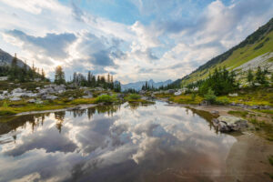 Dramatic clouds reflected in stream in alpine basin of Mount Rohr. Coast Range British Columbia