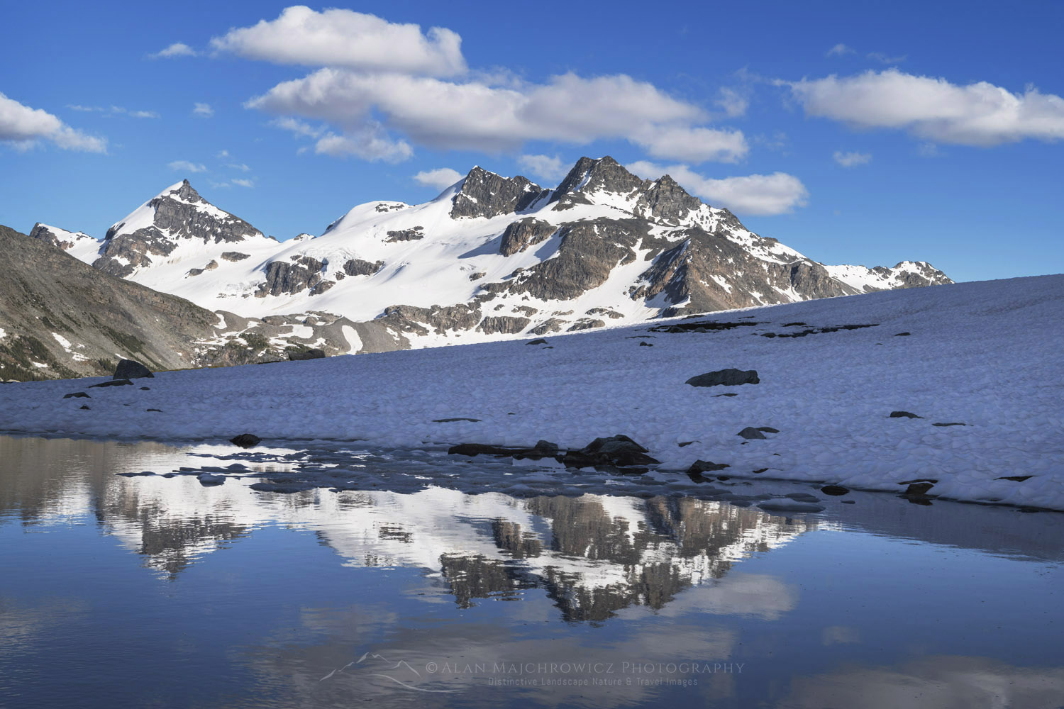 Snow melt tarn on Silent Mountain. Twin Towers, Cony Peak, and Spillimacheen Glacier are in the distance. Purcell Mountains, British Columbia #86124